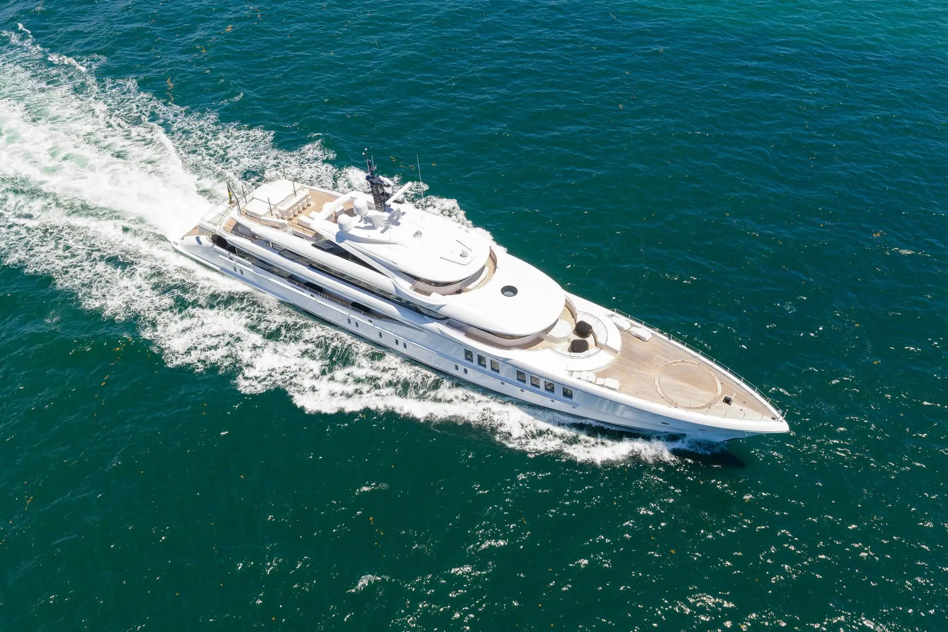 Phygital Group A large white luxury yacht moves quickly across deep blue ocean water, creating a wake behind it under a clear sky. Full Service Marketing Agency